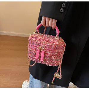 Detail einer rosa Tweed-Beuteltasche mit goldenem Reißverschluss und Kettenriemen