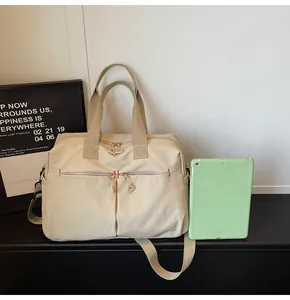 Dettaglio borsa da viaggio in tela con cuciture rosse e doppie tasche frontali con zip