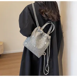 Détails du sac seau en tissu gris avec clous cœurs argentés et fermeture à cordon