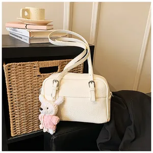 Detail view of cream lychee texture square bag with silver buckles and a cute bunny charm