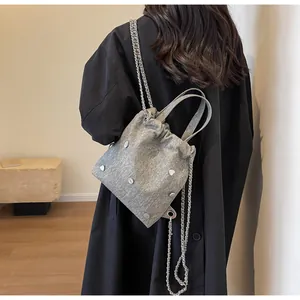 Sac seau gris chic en tissu avec clous en cœur et chaîne argentée sur manteau noir