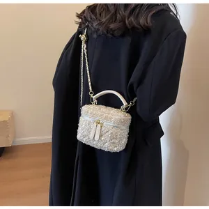 Detail der Tweed-Eimertasche mit Webstruktur und Goldkette auf schwarzem Mantel