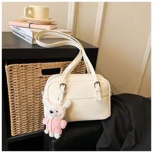 Detail of lychee pattern leather bag with a cute white bunny charm in indoor setting
