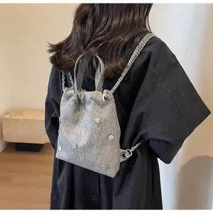 Détail du sac à dos gris en denim avec cordon, chaîne argentée et clous en métal