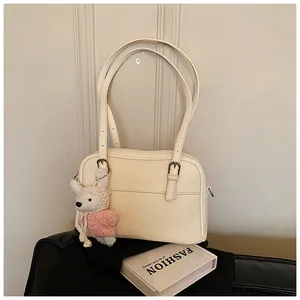 Detail of cream lychee texture leather shoulder bag with a cute white rabbit plush charm