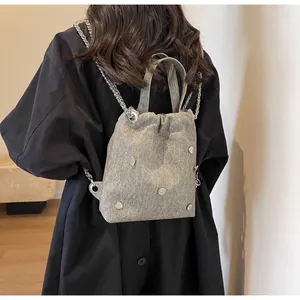 Détail d'un sac à dos en tissu gris avec cordon de serrage et rivets en forme de cœur
