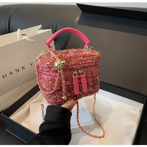 Detail der rosa Tweed-Kosmetiktasche mit Goldbeschlägen und Kette auf Geschenkbox