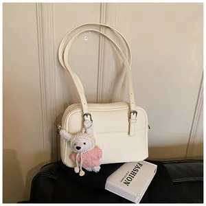 Detail of lychee pattern beige bag with cute white rabbit plush charm and silver buckle