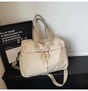 Dettaglio della borsa da viaggio in tela beige con cuciture rosse sulle tasche frontali