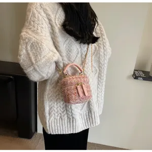 Schicke Tweed-Beuteltasche in Rosa mit Ledergriff und goldener Kette an der Schulter