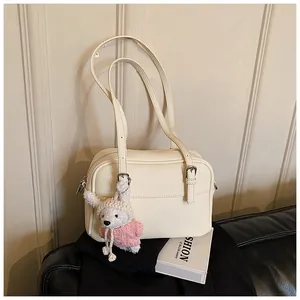 Close-up of cream lychee texture leather shoulder bag with a cute knit bunny pendant