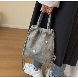 Détail du sac seau en denim gris avec clous en cœur en métal et bandoulière chaîne