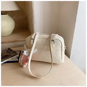 Detail of lychee textured cream shoulder bag with a cute plush rabbit pendant charm