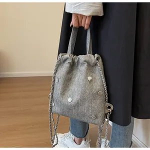 Détail du sac en denim gris avec fermeture à cordon et bouton en métal en forme de cœur