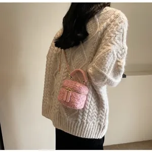 Detailansicht der rosa Tweed-Minitasche mit goldener Kette und gewebter Textur-Details
