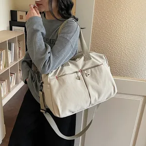 Grande borsa da viaggio in tela beige con tracolla regolabile in un ambiente interno