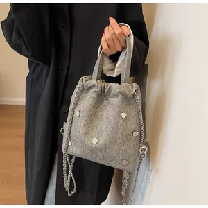 Détail du sac seau gris texturé avec clous coeurs argentés et bandoulière chaîne