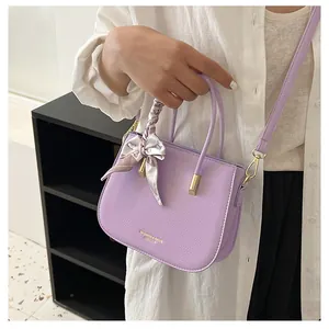 Dettaglio borsa squadrata in pelle lavanda con foulard in seta e logo dorato inciso