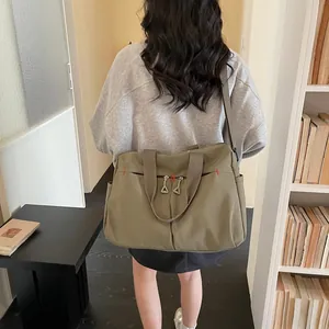Borsa da viaggio in tela verde oliva ad alta capacità indossata da un modello in interno