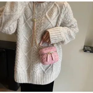 Detail der rosa Tweed-Beuteltasche mit goldener Kette und strukturiertem Stoffgriff