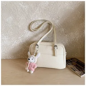 Detail of cream white lychee leather handbag with a cute plush rabbit charm on the strap