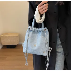 Détail du mini sac à dos en jean bleu clair avec bretelles en chaîne argentée et œillets