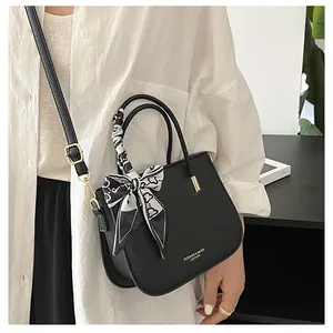 Dettaglio della borsa nera martellata con foulard di seta e finiture in metallo oro