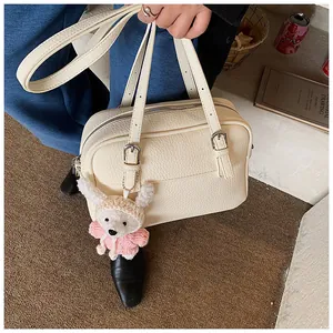Detail of cream white lychee grain crossbody bag with cute plush bear pendant accessory
