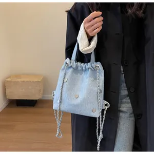 Détail d'un mini sac à dos en jean bleu clair avec œillets et bandoulières chaîne