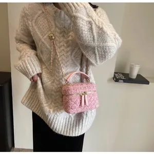Detail der rosa Tweed-Beuteltasche mit Goldkugel-Kettenversteller und Webstruktur