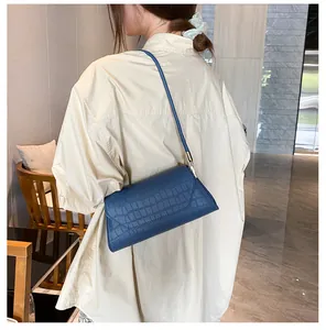 Details der dunkelblauen Schultertasche mit Krokoprägung zu einem weißen Hemd