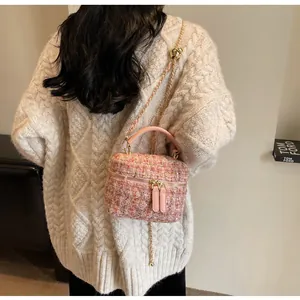 Detail der rosa Tweed-Beuteltasche mit Goldkette, getragen zum cremefarbenen Strickpullover