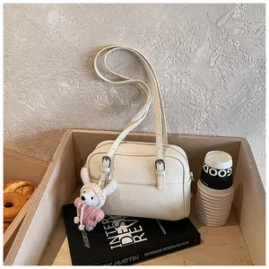 Close-up of cream lychee texture handbag with a cute crochet rabbit charm and metal buckles