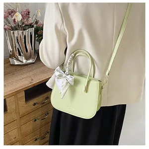 Dettaglio borsa in pelle verde menta con foulard decorativo e scritte dorate