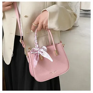 Dettaglio borsa in pelle rosa con manico in seta e finiture in metallo dorato