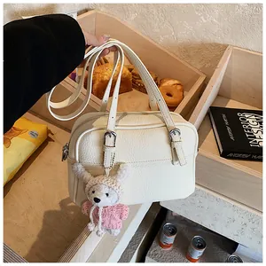 Macro detail of white lychee pattern leather handbag with silver hardware and bear charm
