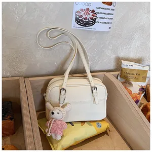 Detail of off-white lychee texture leather bag with a cute pink bear plush charm