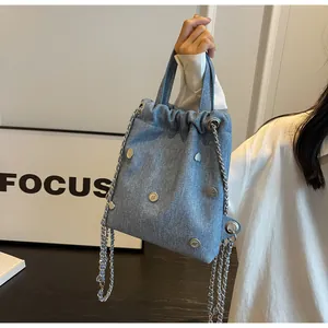 Détail d'un sac seau en jean bleu avec œillets métalliques et rivets en forme de cœur