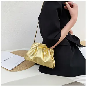 Detail of metallic gold cloud bag with pleated texture and a delicate metal chain strap