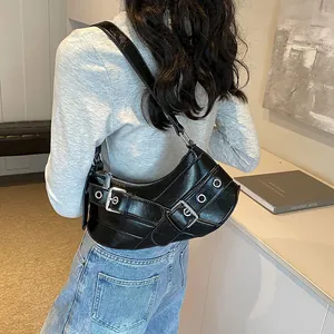 Chic black motorcycle style underarm bag with silver buckles worn by a model