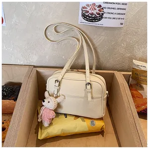 Detailed view of cream crossbody bag with litchi texture and cute rabbit charm pendant