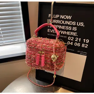 Detail der rosa Tweed-Eimertasche mit goldener Kettenriemen und Metall-Verstellkugel