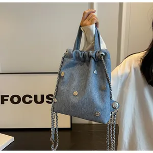 Détails du sac seau en denim bleu clair avec rivets et breloques en forme de coeur