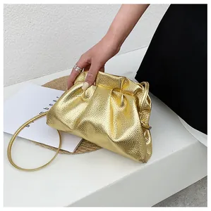 Detail of gold cloud bag featuring metallic lychee texture and pleated drawstring design