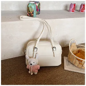 Detail of off-white lychee pattern shoulder bag with a cute bunny charm and silver buckle