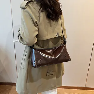 Sac fourre-tout vintage marron foncé en similicuir brillant porté par un mannequin