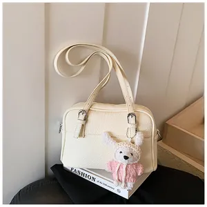 Detail of lychee textured cream crossbody bag with a cute plush bunny pendant