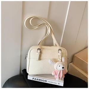 Detail showing creamy litchi grain leather crossbody bag with cute rabbit charm