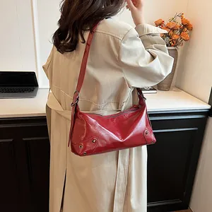 Sac fourre-tout rétro en cuir verni rouge avec rivets porté comme un sac à bandoulière chic