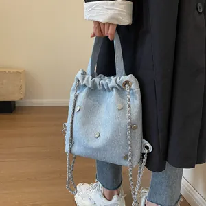 Sac seau en denim bleu clair avec rivets en forme de cœur et bandoulière chaîne